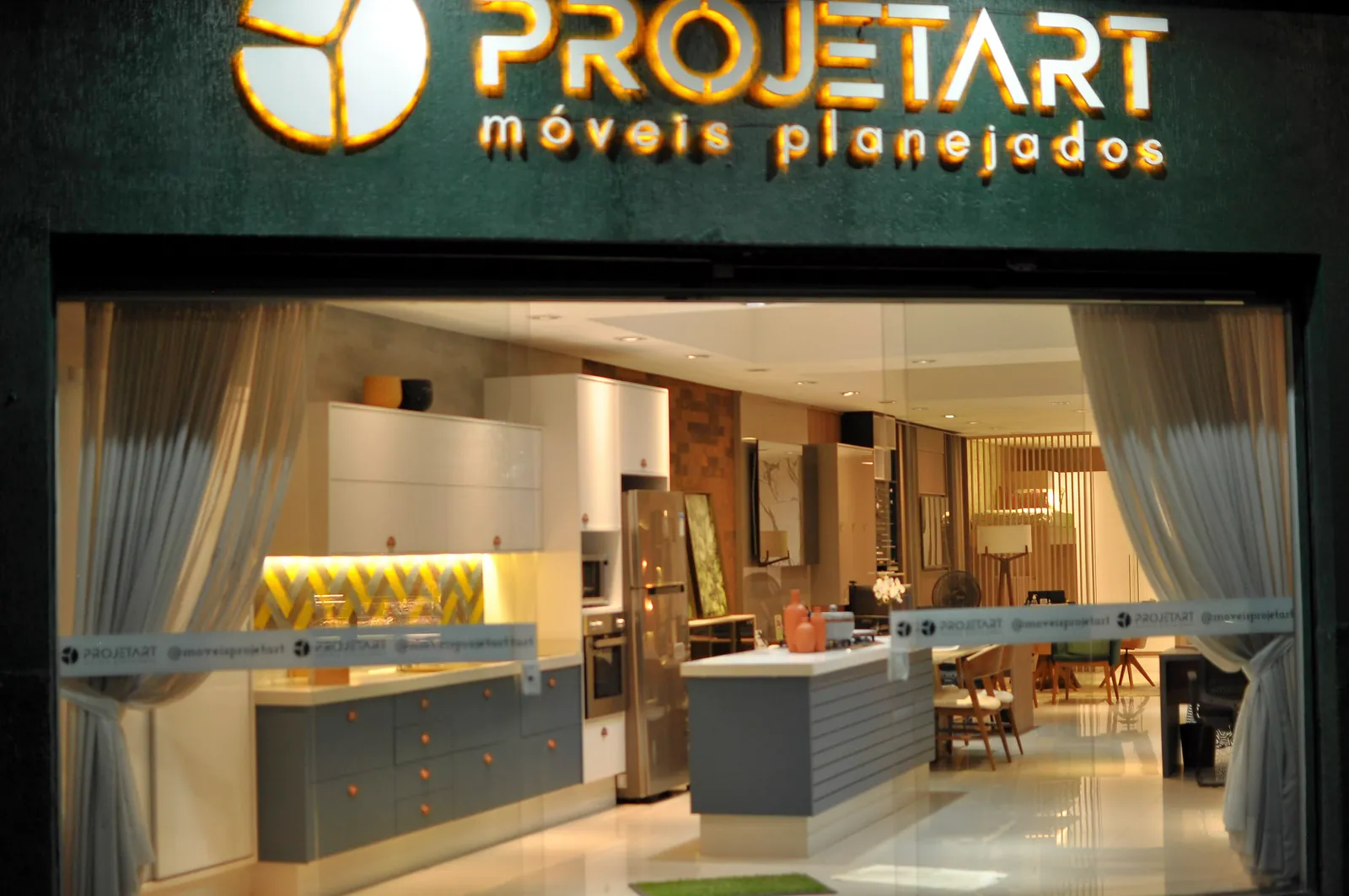 Fachada da loja Projetart iluminada a noite